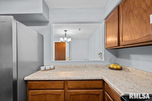 kitchen with stainless steel refrigerator, range, an inviting chandelier, hanging light fixtures, and a textured ceiling