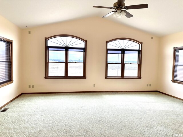 carpeted empty room featuring ceiling fan, plenty of natural light, and lofted ceiling