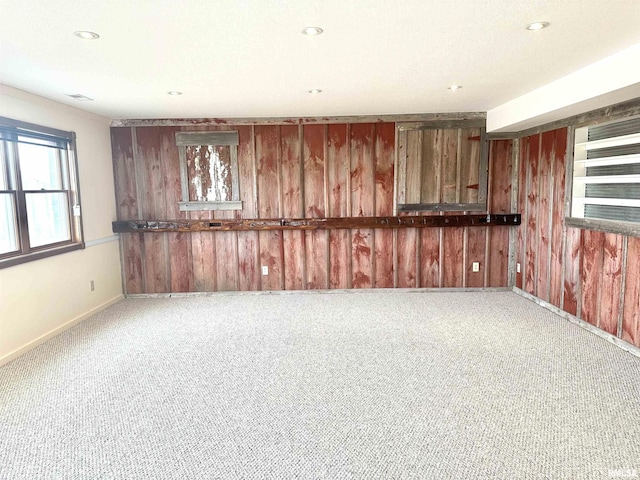 carpeted spare room featuring wood walls