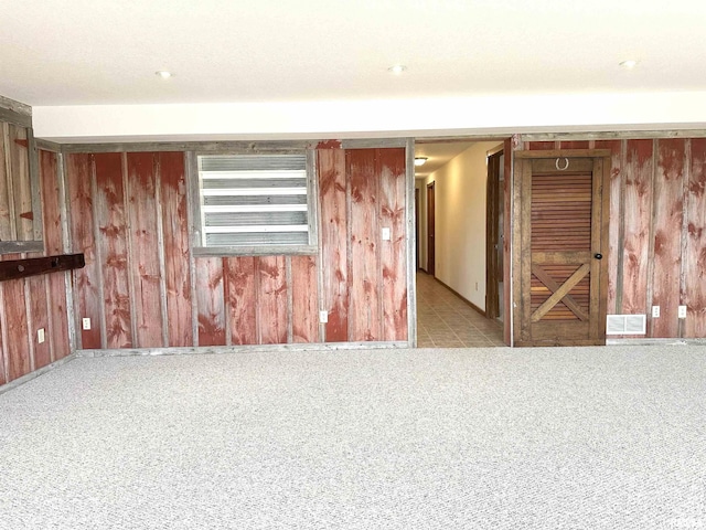 carpeted spare room featuring wood walls