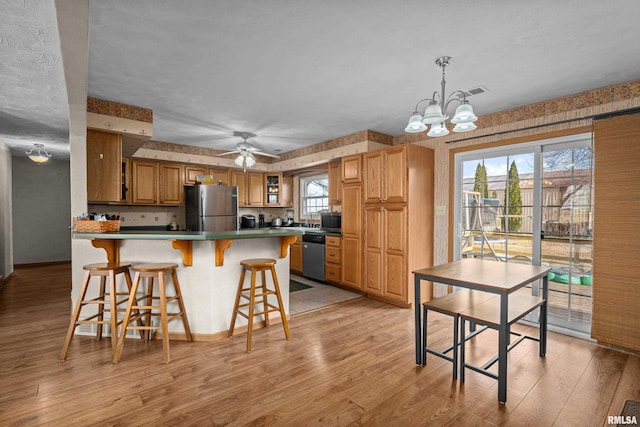 kitchen featuring a healthy amount of sunlight, appliances with stainless steel finishes, hanging light fixtures, and light wood-type flooring