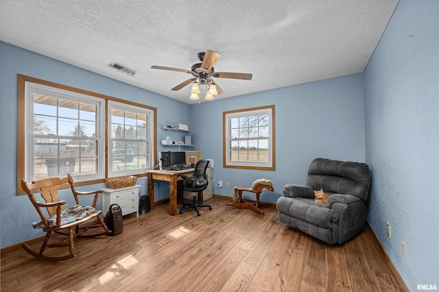 office area featuring ceiling fan, light hardwood / wood-style floors, and a textured ceiling