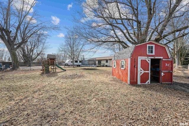 view of yard featuring a storage unit, a playground, and a trampoline