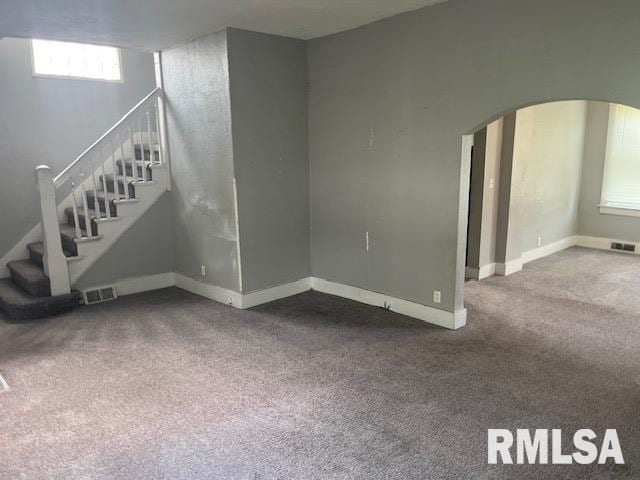 1015 Arlington Ct, Davenport, IA 52803 - unfurnished living room with visible vents, carpet flooring, arched walkways, and stairway