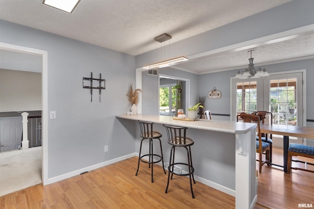 kitchen featuring light hardwood / wood-style flooring, a breakfast bar, pendant lighting, and kitchen peninsula