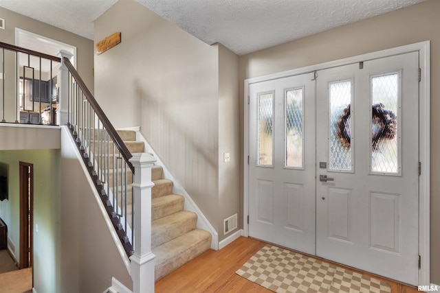 entrance foyer with a textured ceiling and light hardwood / wood-style flooring