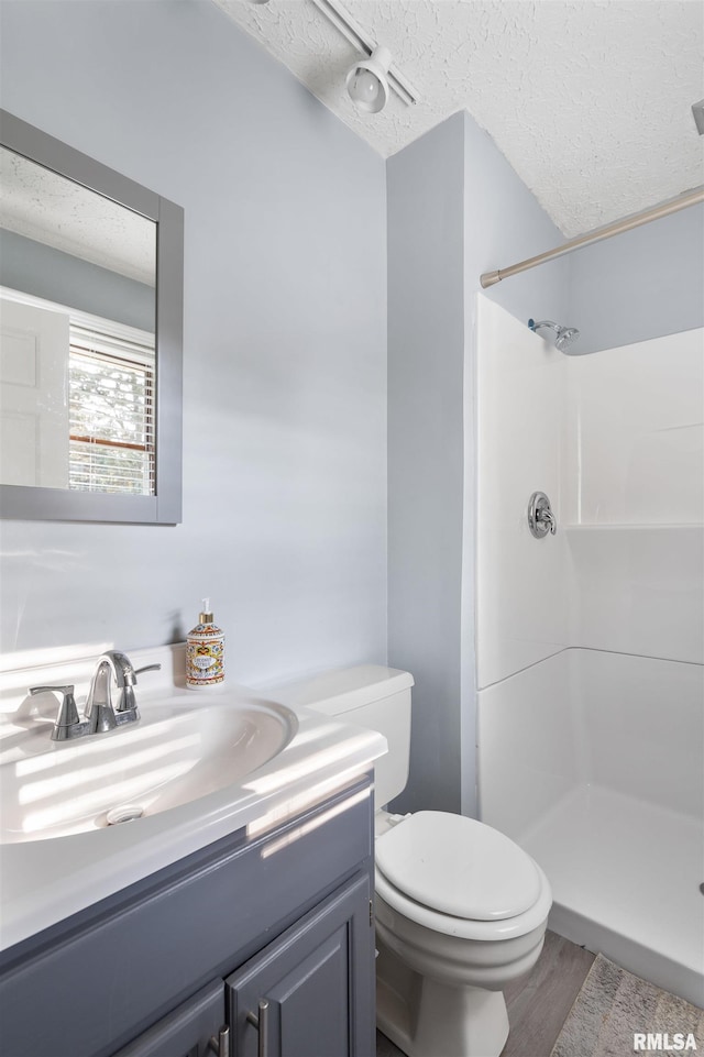 bathroom featuring hardwood / wood-style flooring, vanity, walk in shower, toilet, and a textured ceiling