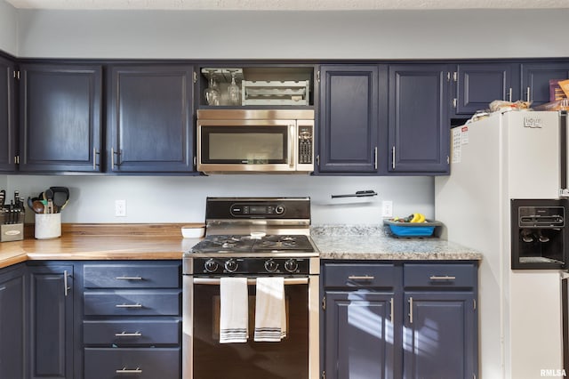 kitchen featuring blue cabinets, gas stove, and white refrigerator with ice dispenser