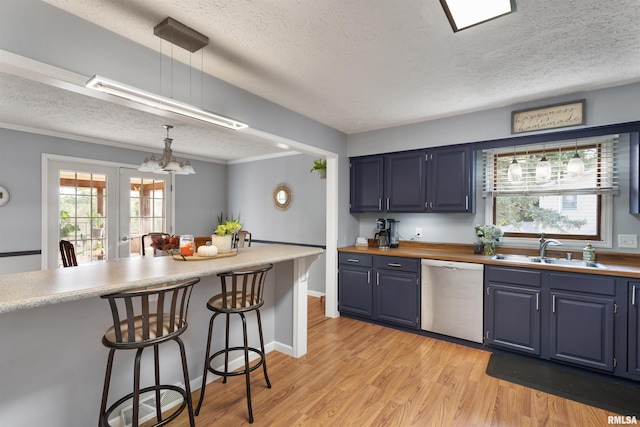 kitchen featuring pendant lighting, stainless steel dishwasher, sink, and a breakfast bar area