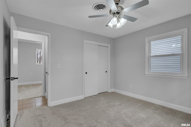 unfurnished bedroom featuring light carpet, a closet, and ceiling fan