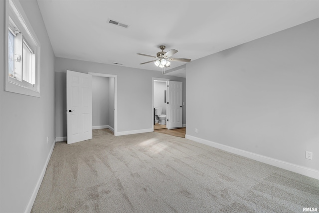 unfurnished bedroom featuring connected bathroom, light colored carpet, and ceiling fan