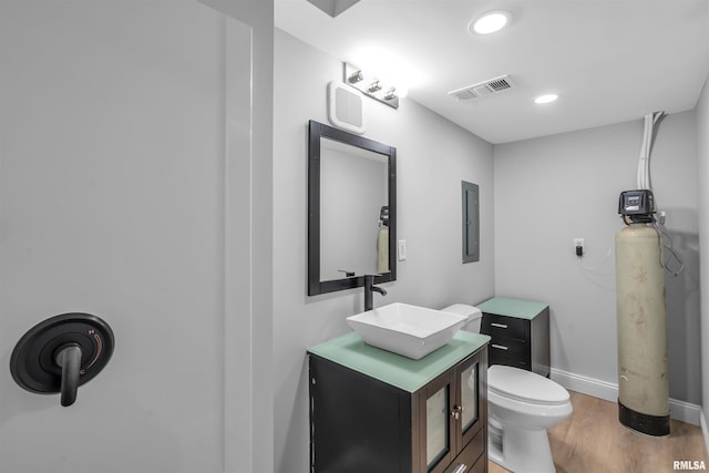 bathroom with vanity, toilet, electric panel, and hardwood / wood-style floors