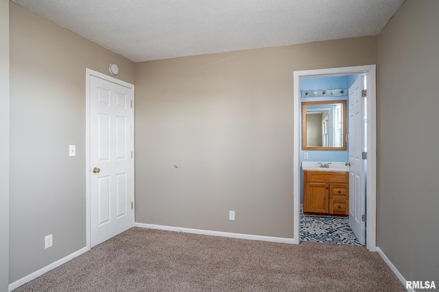 unfurnished bedroom featuring sink, light carpet, a textured ceiling, and ensuite bath