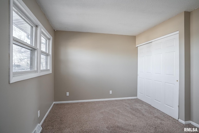 unfurnished bedroom featuring carpet floors, a textured ceiling, and a closet