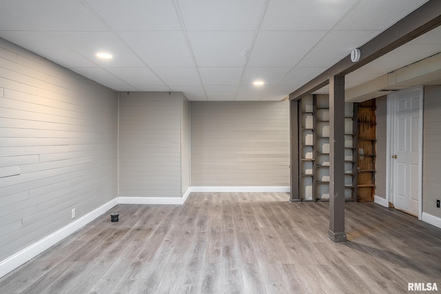 basement with a paneled ceiling and light hardwood / wood-style floors