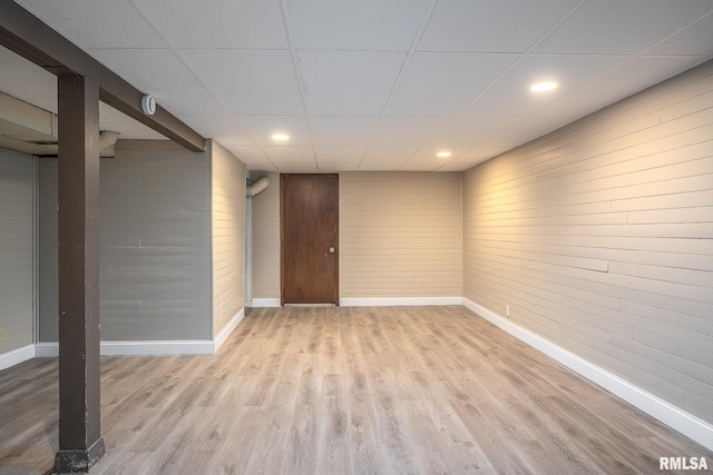 basement featuring a drop ceiling and light hardwood / wood-style flooring