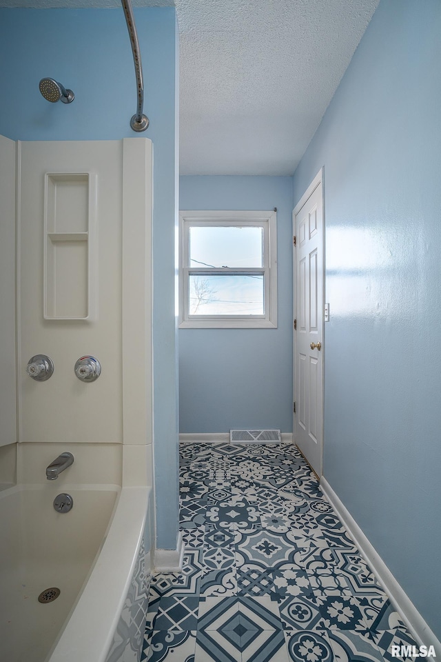 bathroom featuring  shower combination and a textured ceiling