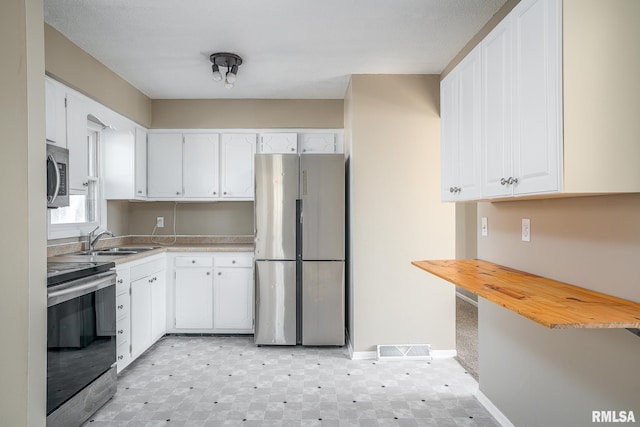 kitchen with stainless steel appliances, sink, and white cabinets