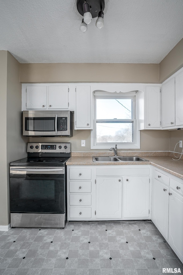 kitchen with stainless steel appliances, sink, a textured ceiling, and white cabinets