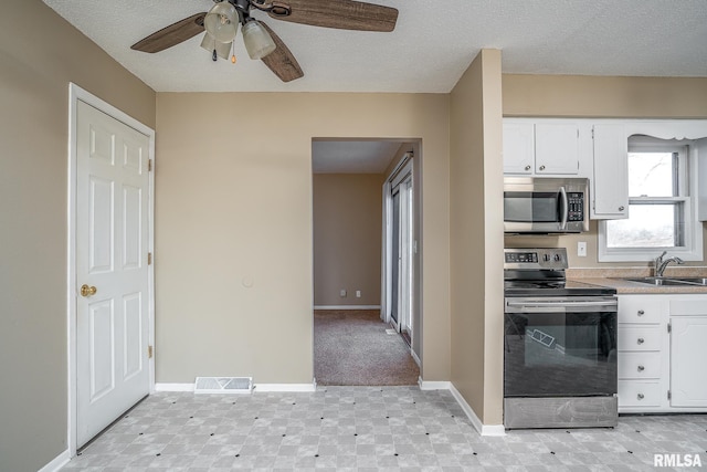 kitchen with appliances with stainless steel finishes, sink, white cabinets, ceiling fan, and a textured ceiling