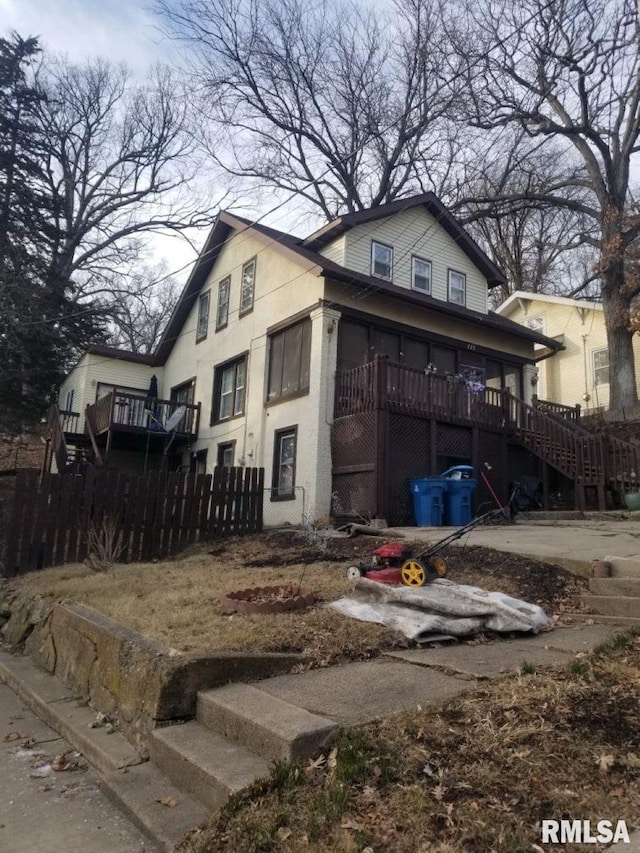 view of home's exterior featuring stairway, fence, stucco siding, and a wooden deck