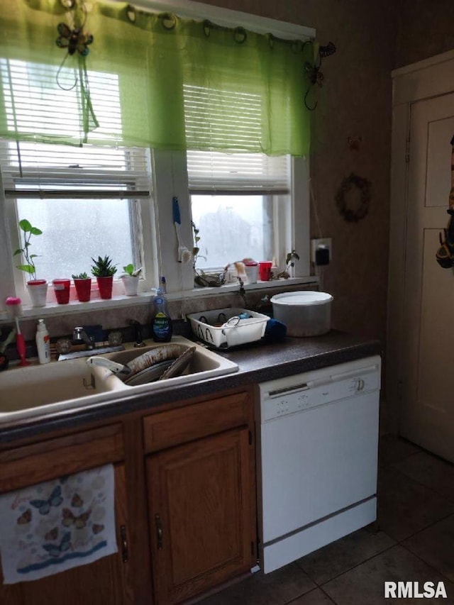 kitchen featuring dishwasher, sink, and dark tile patterned floors