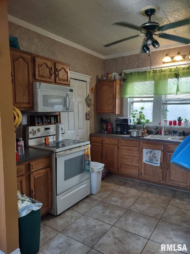 kitchen featuring crown molding, white appliances, sink, and light tile patterned floors