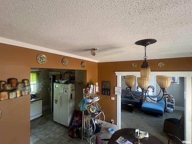interior space with dark tile patterned floors, white fridge with ice dispenser, a textured ceiling, and a wealth of natural light