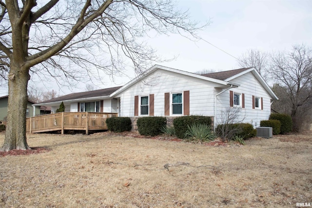 view of side of home featuring a wooden deck, a lawn, and cooling unit