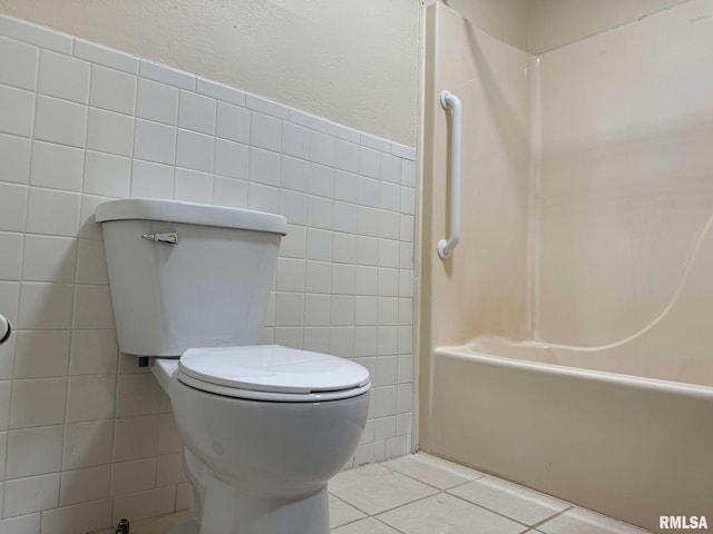 bathroom with tile patterned floors, toilet, and tile walls