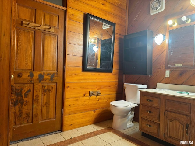 bathroom featuring vanity, wooden walls, tile patterned floors, and toilet