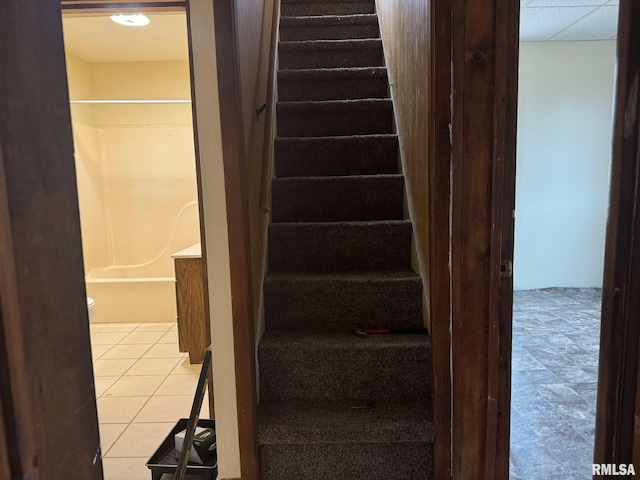 staircase with tile patterned flooring and a drop ceiling