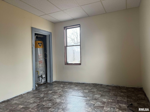 spare room featuring water heater and a drop ceiling