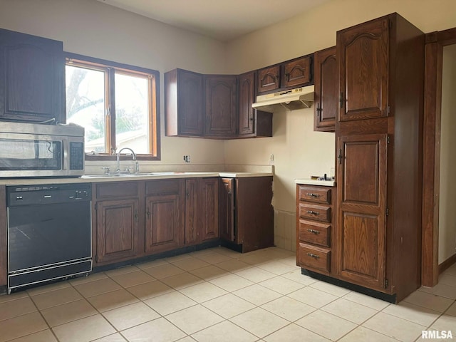 kitchen featuring dark brown cabinetry, sink, light tile patterned floors, and black dishwasher