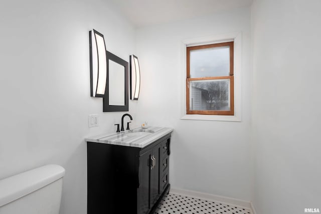 bathroom featuring toilet, vanity, and baseboards