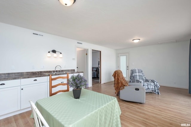 dining space with light wood-style floors, visible vents, and baseboards
