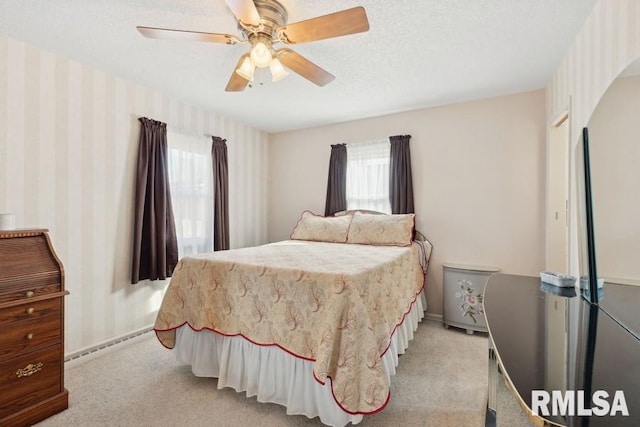 bedroom with a ceiling fan, light carpet, baseboards, wallpapered walls, and a textured ceiling