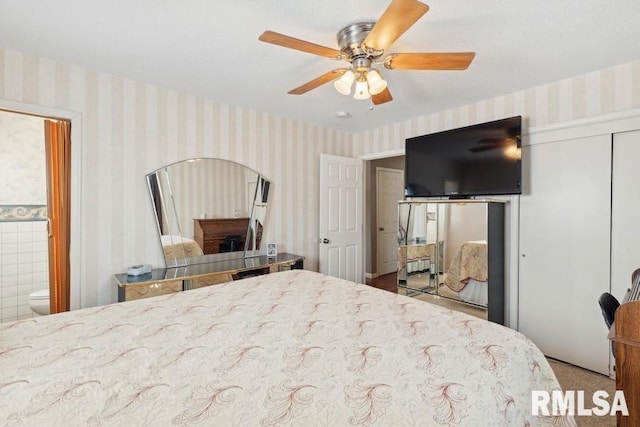 bedroom featuring wallpapered walls, a ceiling fan, ensuite bathroom, and a closet