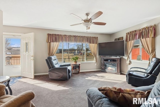 carpeted living room with baseboards, ceiling fan, a glass covered fireplace, and plenty of natural light