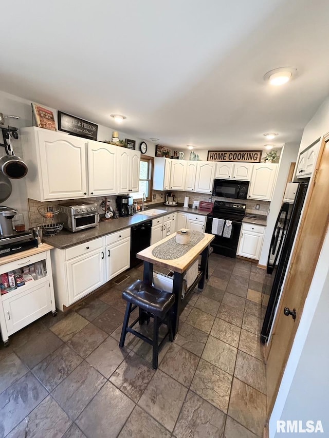 kitchen with black appliances, a sink, dark countertops, backsplash, and white cabinetry