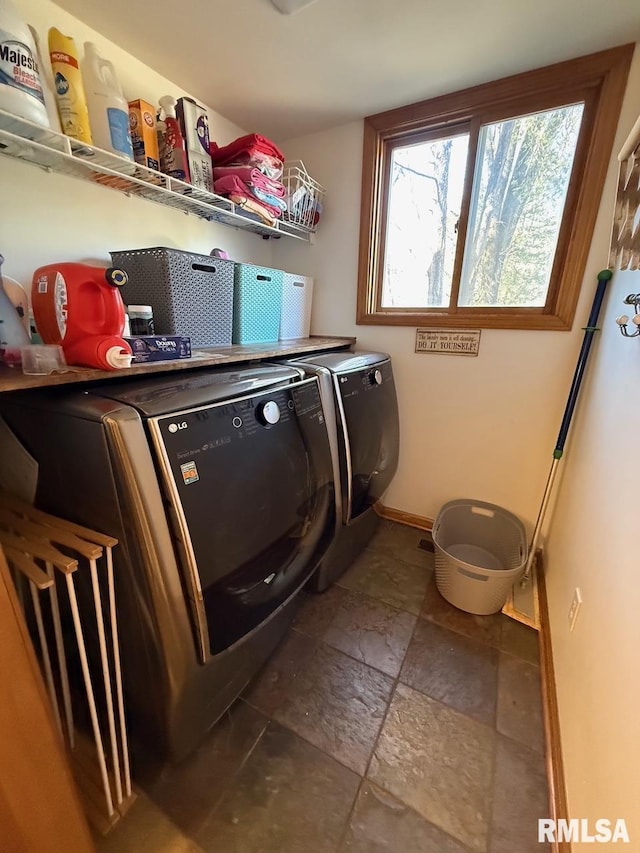 washroom featuring baseboards, separate washer and dryer, stone tile flooring, and laundry area