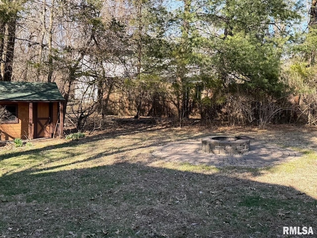 view of yard featuring an outbuilding, a fire pit, and a shed