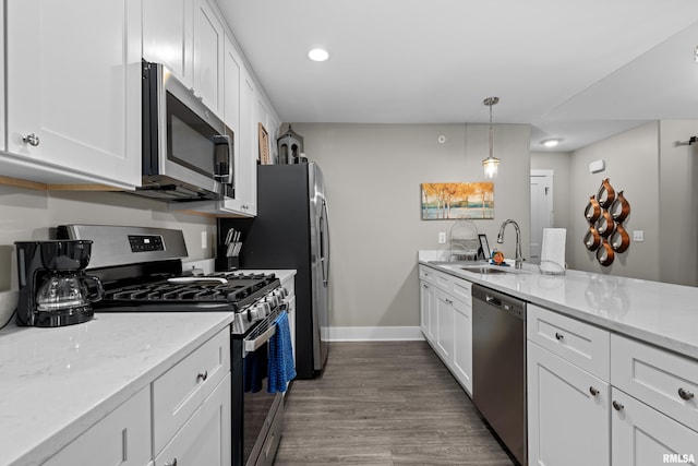 kitchen featuring appliances with stainless steel finishes, pendant lighting, white cabinetry, sink, and dark wood-type flooring