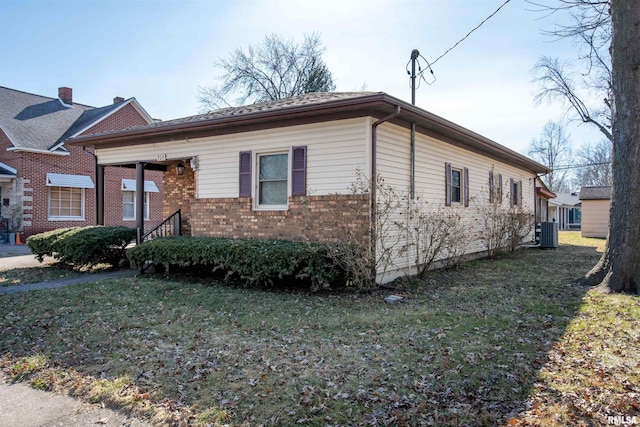 view of front of property with central AC unit, a front yard, and brick siding