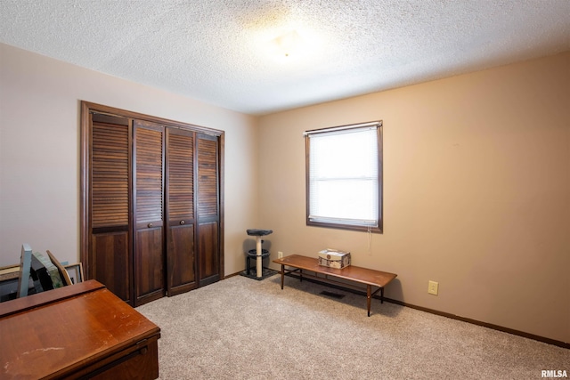 interior space featuring baseboards, a textured ceiling, and light colored carpet