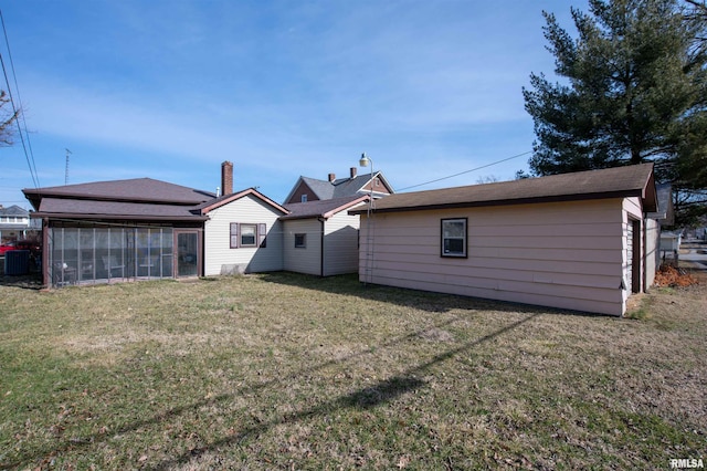 rear view of property with a lawn and a sunroom