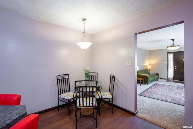 dining space with a textured ceiling, wood finished floors, and baseboards