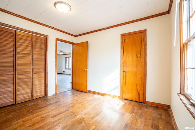 unfurnished bedroom with multiple windows, ornamental molding, and light wood-type flooring