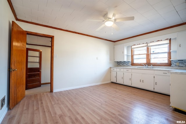 kitchen featuring decorative backsplash, crown molding, white cabinets, and light hardwood / wood-style flooring