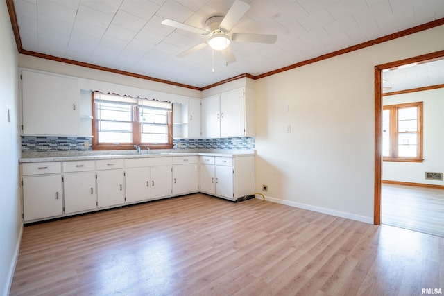 kitchen featuring ornamental molding, white cabinets, light wood-type flooring, and decorative backsplash